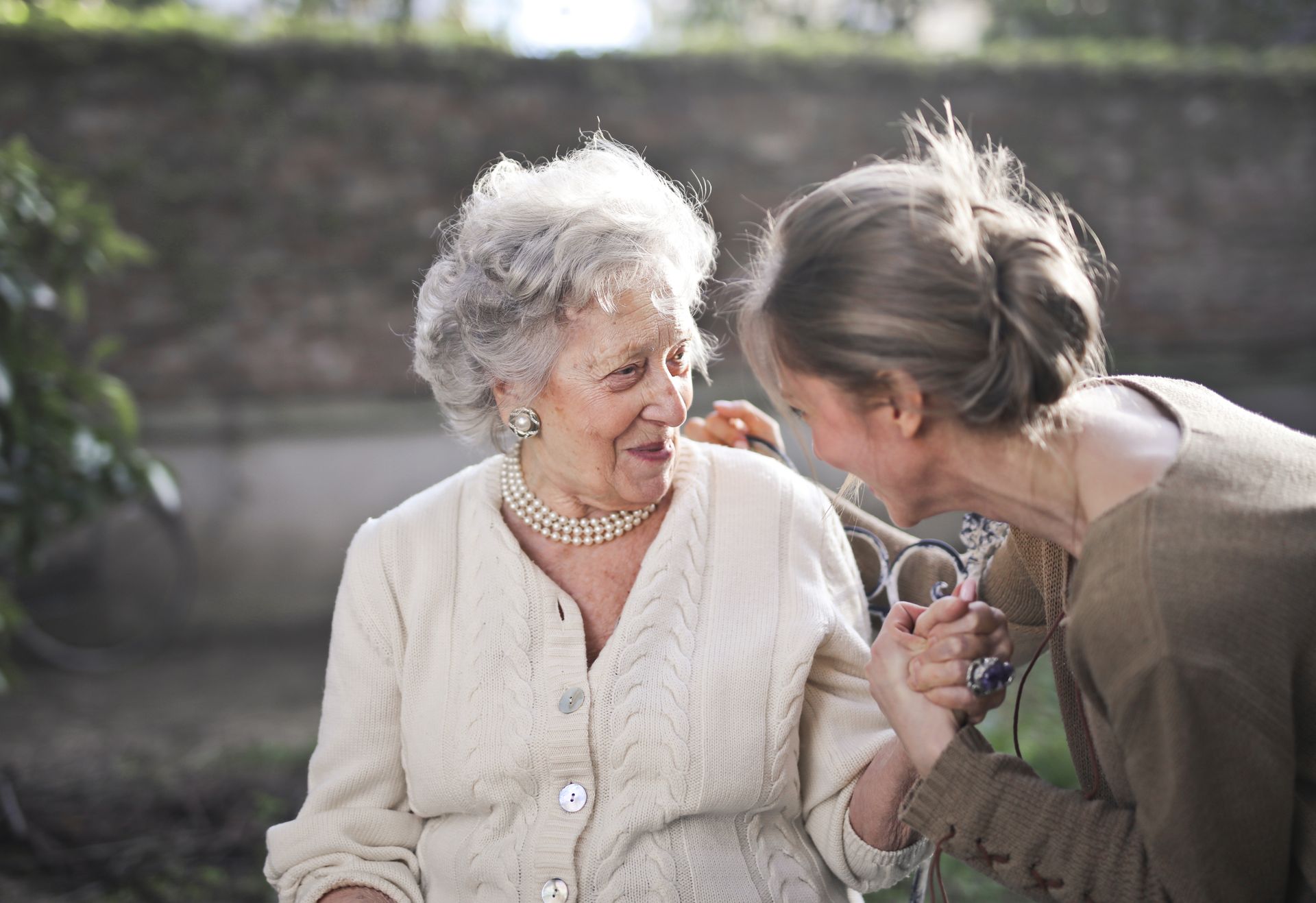 Elderly woman dressed nicely outside with caregiver.